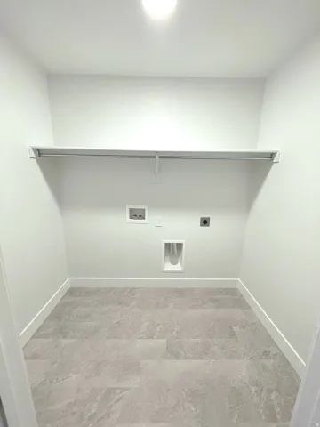 Dedicated utility space featuring light-toned flooring, white walls, and a built-in shelf with hanging rod