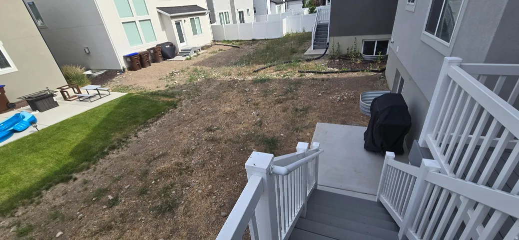 Rear exterior featuring a multi-level composite deck with white railings, a concrete patio, and a sloped yard