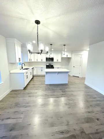 Modern kitchen featuring white cabinetry, a central island, stainless steel appliances, and a black faucet
