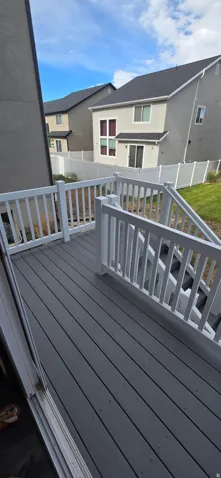 Spacious composite deck featuring white railings and a staircase