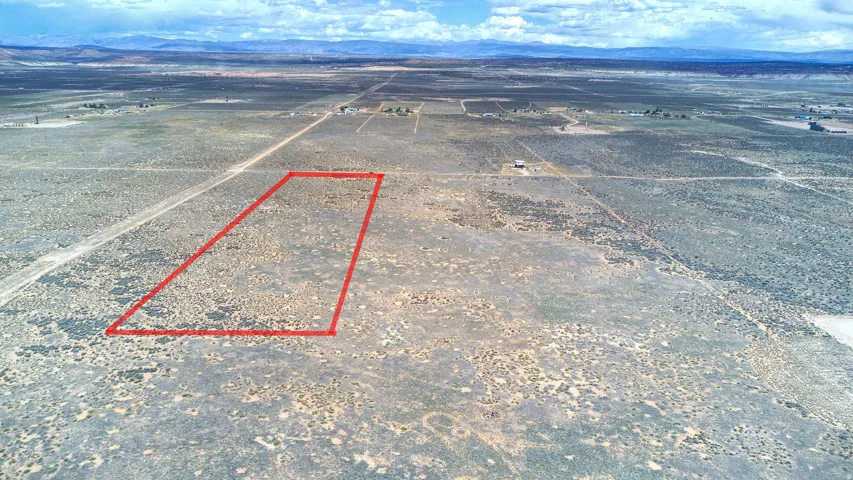 Expansive desert acreage featuring a red-outlined parcel, distant mountain backdrop, and scattered shrub vegetation