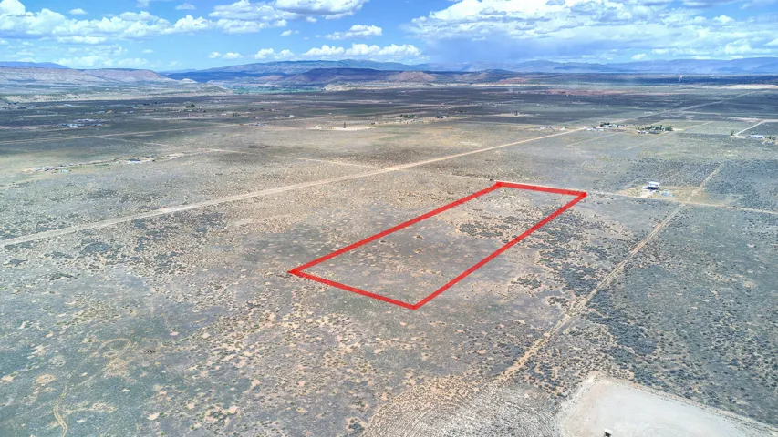 Expansive rural land parcel with a rectangular outline, featuring natural desert vegetation, and distant mountain backdrops