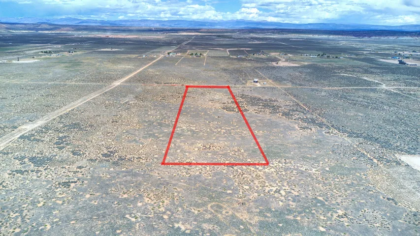 Expansive undeveloped land featuring a red-outlined parcel, surrounded by arid landscape and distant mountains