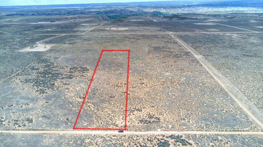 Expansive vacant land with a rectangular perimeter, featuring sparse desert vegetation and a flat topography