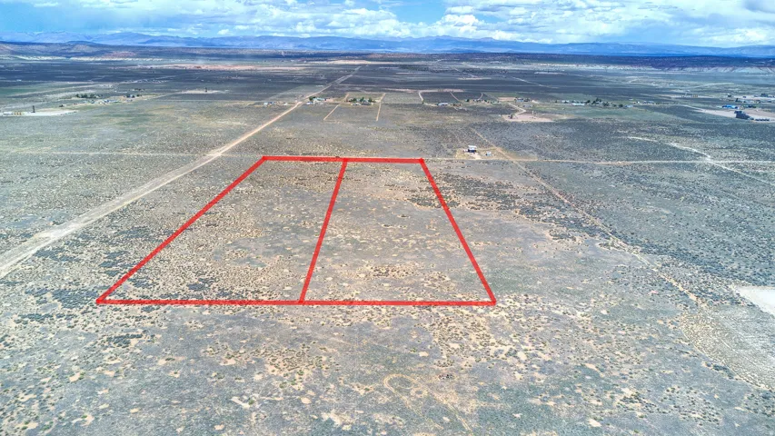 Expansive land parcel with defined boundaries, featuring natural vegetation and distant mountain ranges