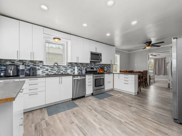 Modern kitchen featuring white cabinetry, stainless steel appliances, and a mosaic tile backsplash