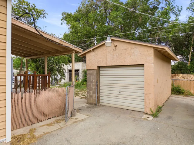 Detached garage with a roll-up door and stucco exterior, featuring an exterior light fixture