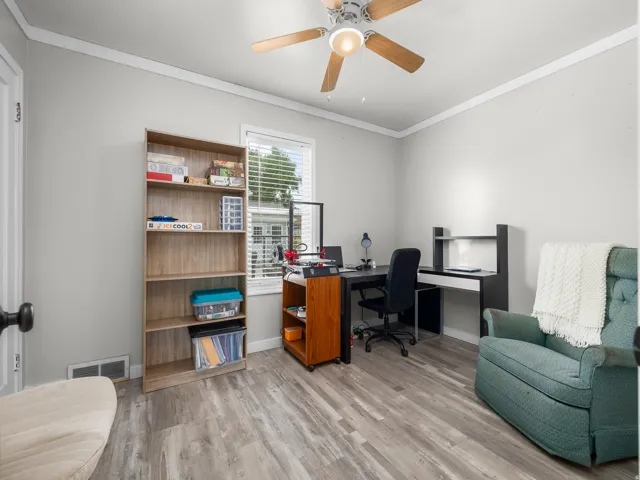 Neutral wall paint, ceiling fan with light fixture, crown molding, wood-finish flooring, and a window with blinds