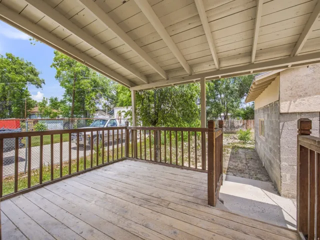 Covered wood-plank porch with wood railing and exposed rafter ceiling