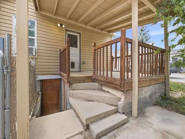 Covered exterior patio featuring wood railings and concrete steps