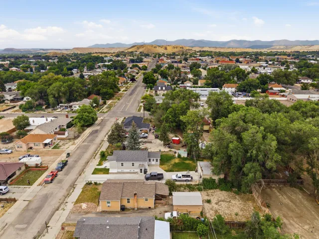 Aerial perspective showcasing a residential neighborhood with mature trees and distant mountain ranges