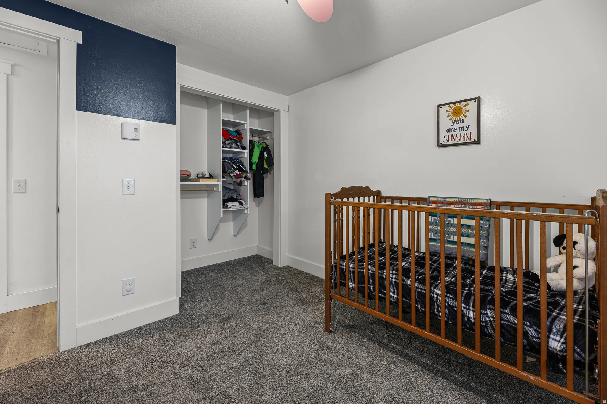 Bedroom featuring plush gray carpeting, white walls, and a partial accent wall in deep blue