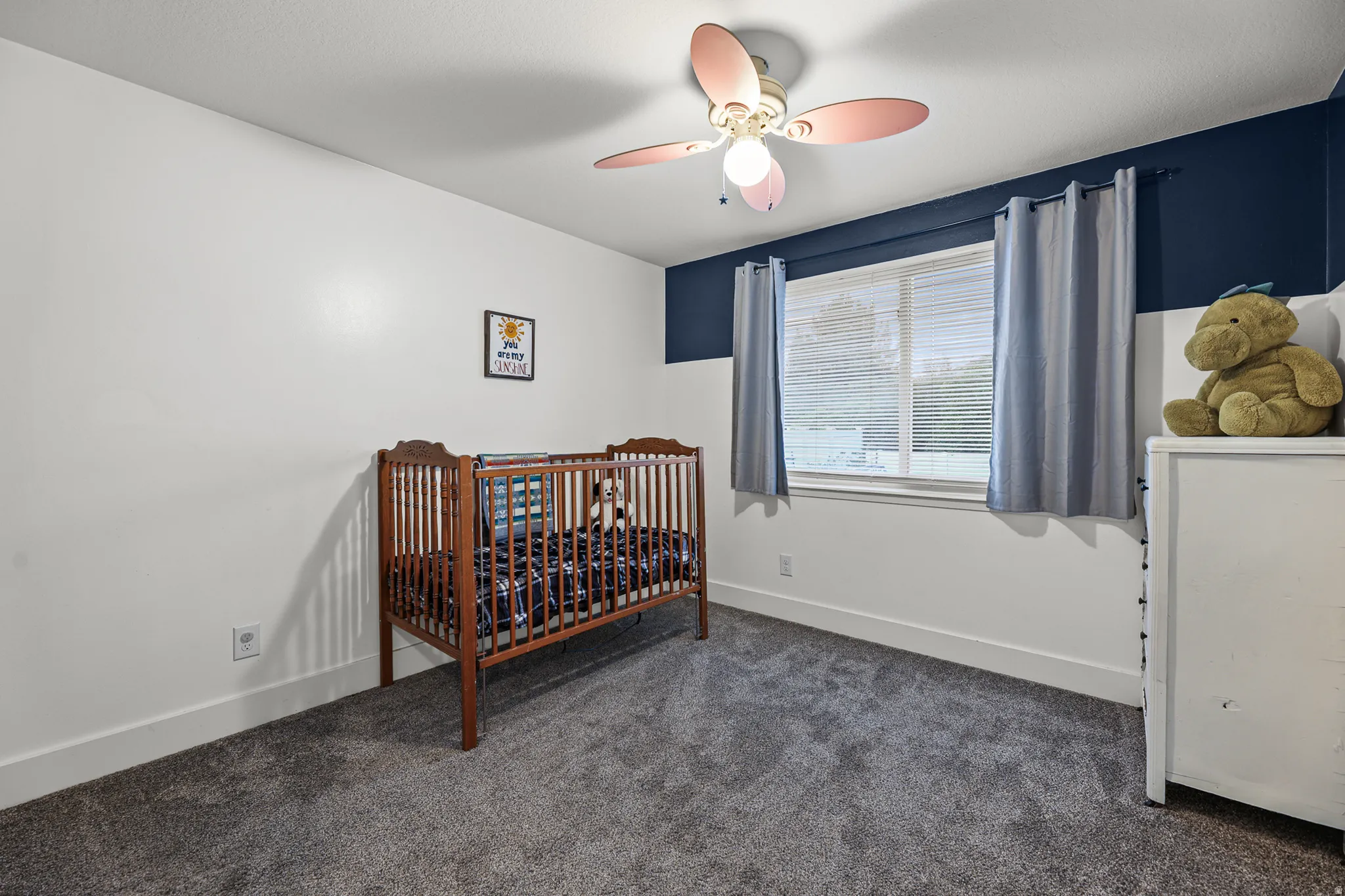 Room featuring gray carpeting, window with blinds, and a ceiling fan