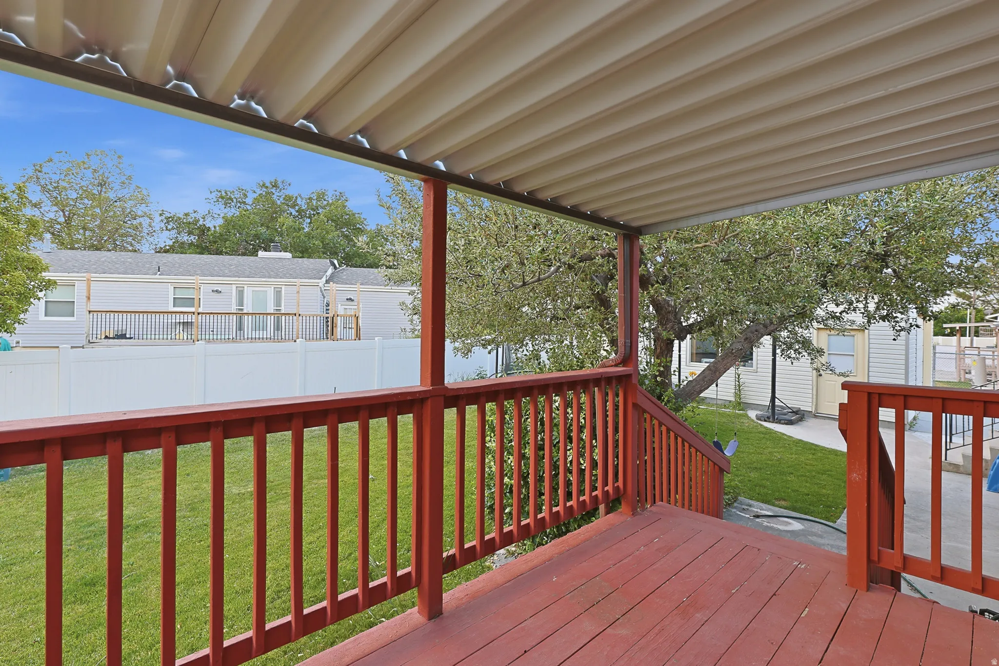 Expansive covered deck featuring a red-stained wood-finish floor and railing system