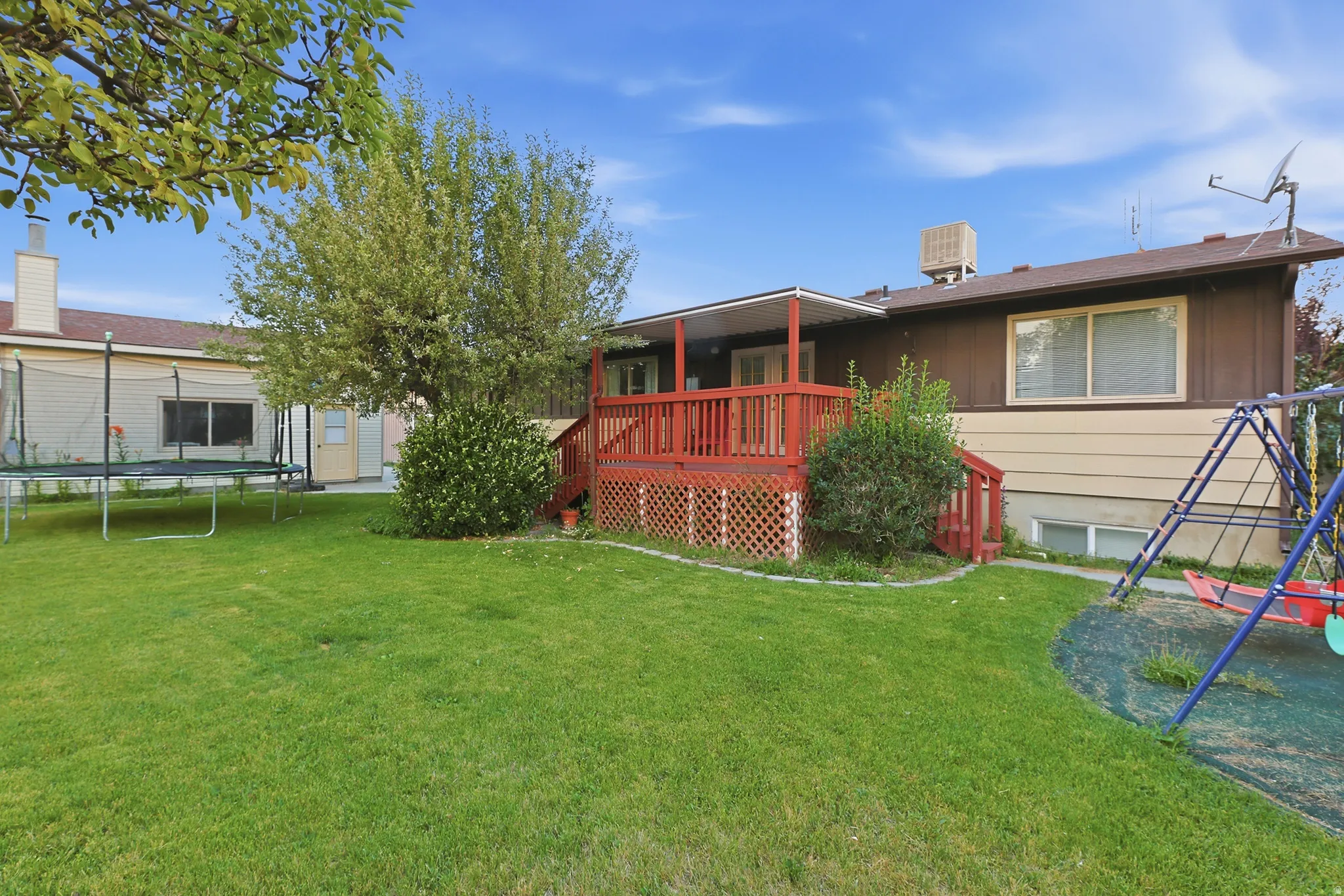 Expansive green lawn with a large, mature tree providing natural shade
