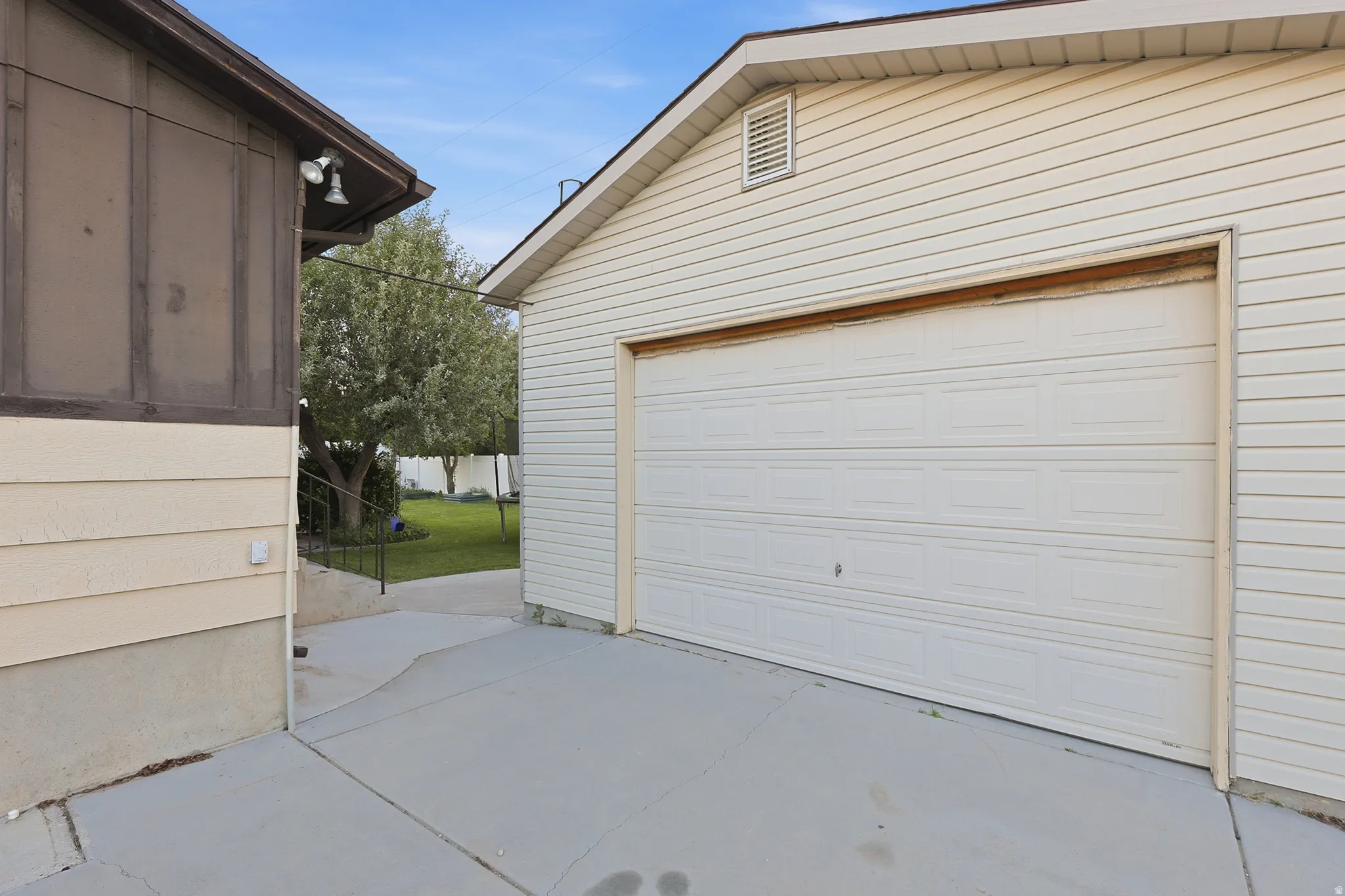 Detached garage featuring white paneling, a vented gable, and concrete driveway