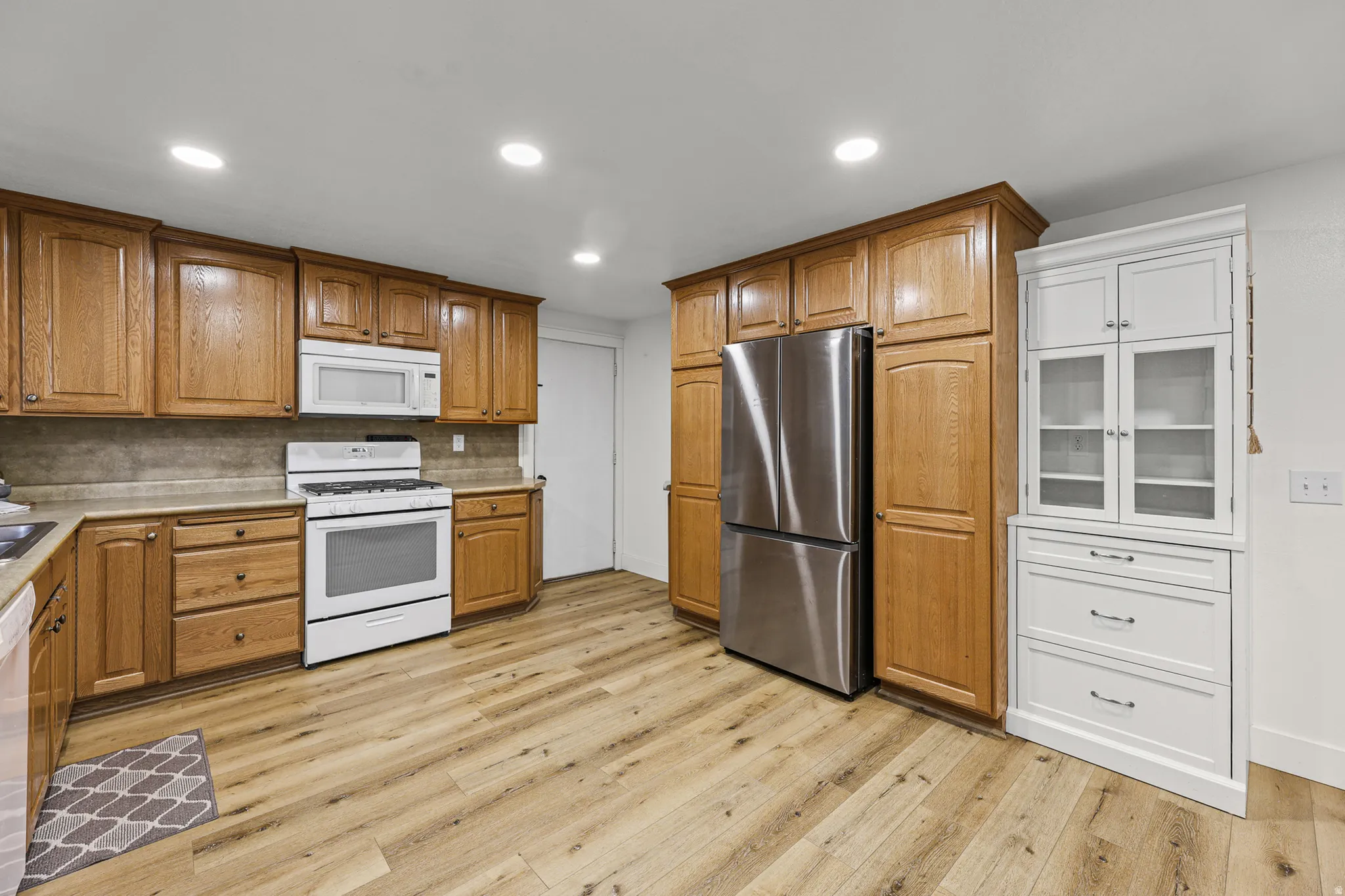 Kitchen featuring wood-finish flooring, recessed lighting, and a combination of wood cabinetry and a white built-in cabinet with glass doors
