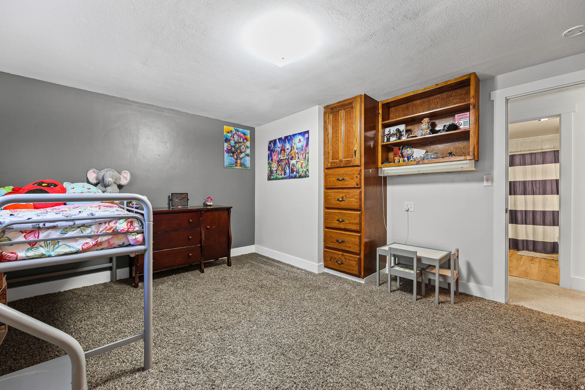 Carpeted room with built-in wood cabinetry and shelving, featuring a neutral gray wall color