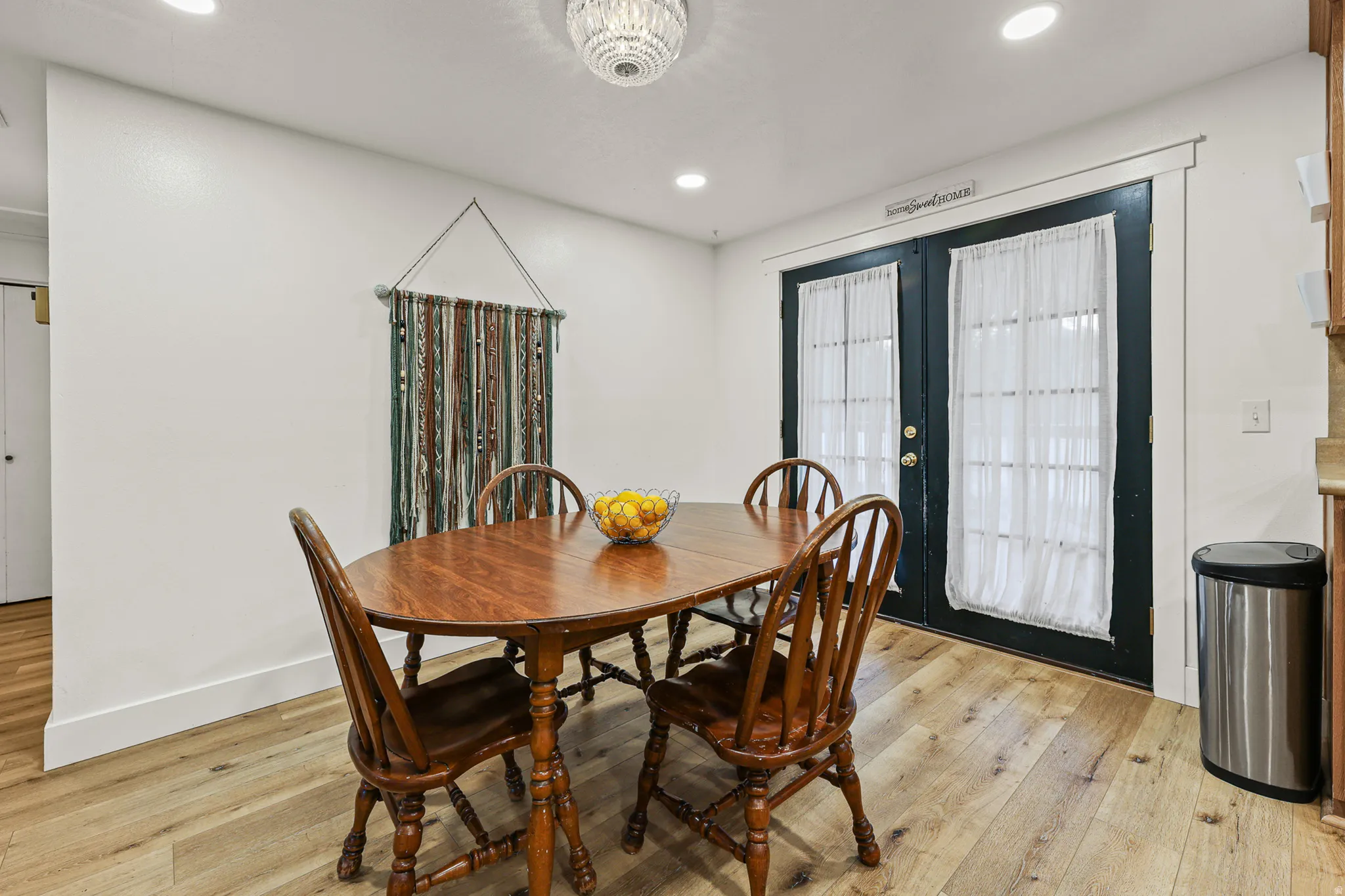 Bright dining area featuring light wood-finish flooring with french doors leading to back covered deck.