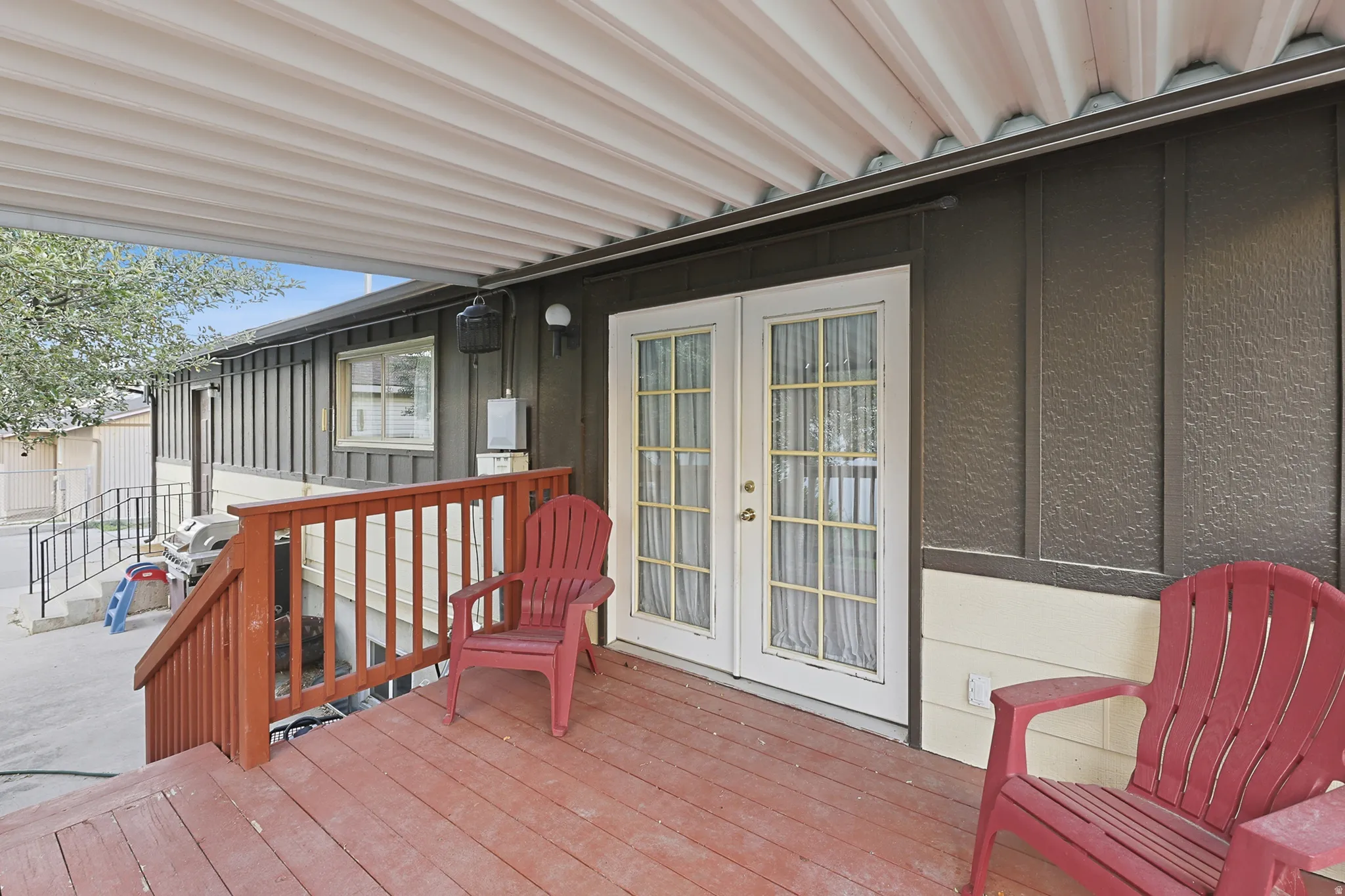 Covered wood-finish deck with a wood railing and white French doors