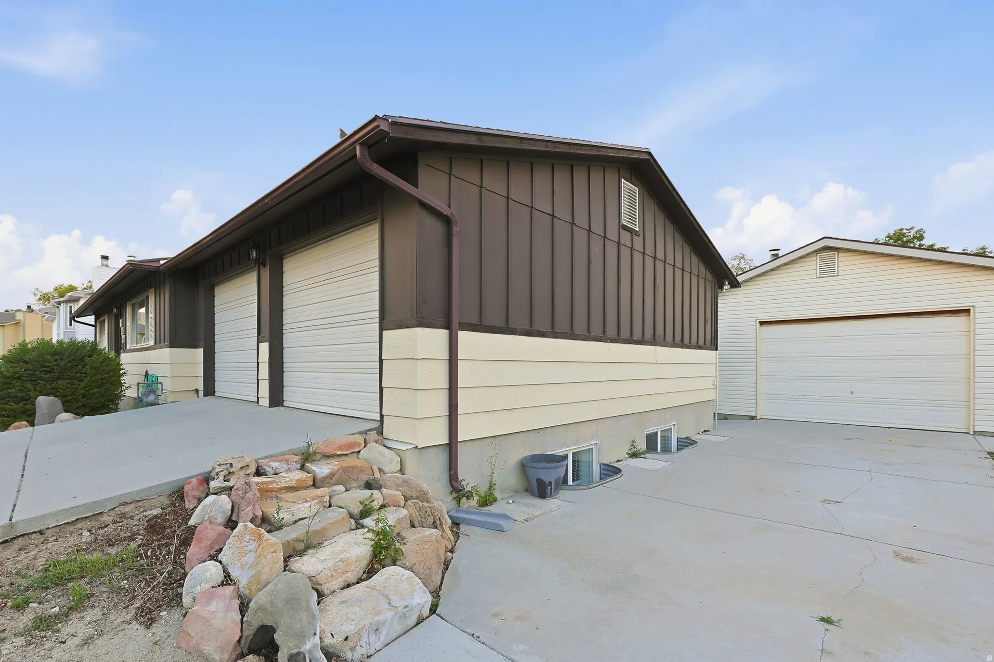 Tons of garage space! Property exterior featuring dark brown board-and-batten siding with light beige horizontal siding accents