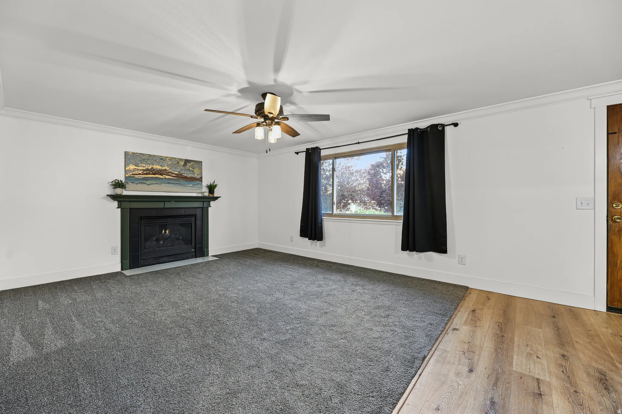 Front entrance living room featuring newer gray carpeting, crown molding, and a ceiling fan