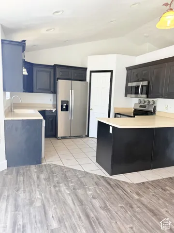 Kitchen featuring dark cabinetry, light-toned countertops, and stainless steel appliances including a refrigerator and built-in microwave