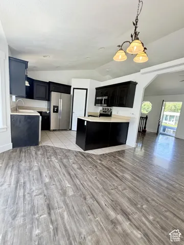 Open-concept kitchen featuring dark cabinetry, stainless steel appliances, and light-toned countertops