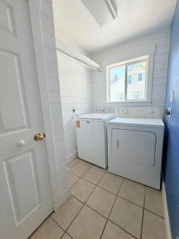 Utility room featuring ceramic tile flooring, a window, and shiplap wall treatment