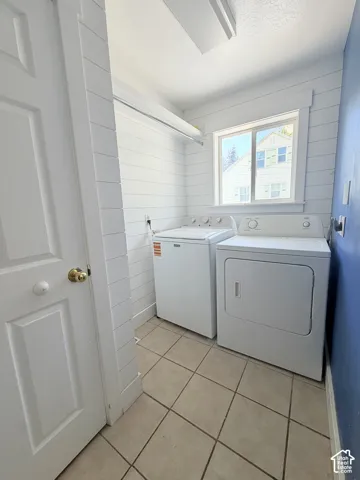 Utility room featuring ceramic tile flooring, a window, and shiplap wall treatment