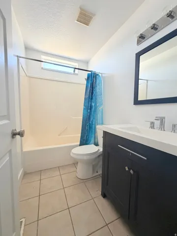 Bathroom featuring a dark wood vanity with a white countertop, chrome fixtures, and a framed mirror