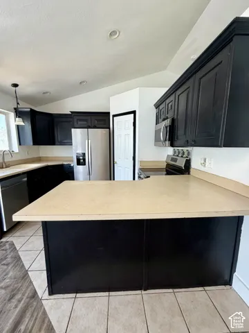 Kitchen featuring black cabinetry, light-toned countertops, and stainless steel appliances