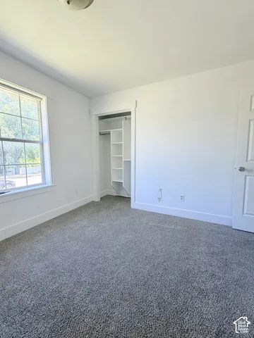 Room featuring neutral gray carpeting, white walls, and a window with white trim