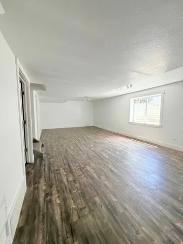 Spacious interior featuring wood-finish flooring, white walls, and a recessed window