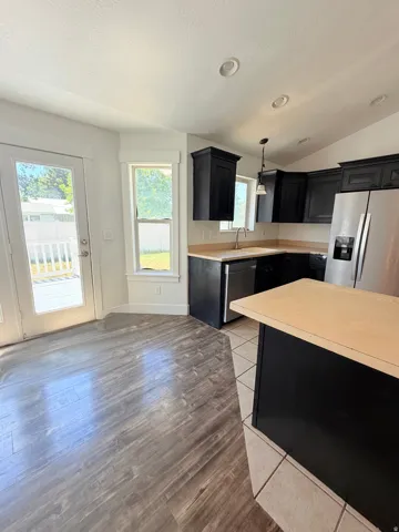 Kitchen featuring dark cabinetry, stainless steel appliances, and light wood-finish countertops