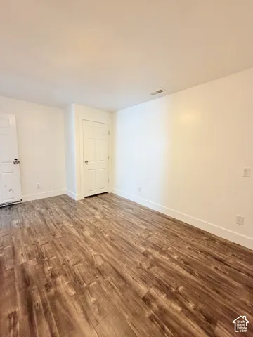 Spacious room featuring wood-finish flooring, white walls, and white trim