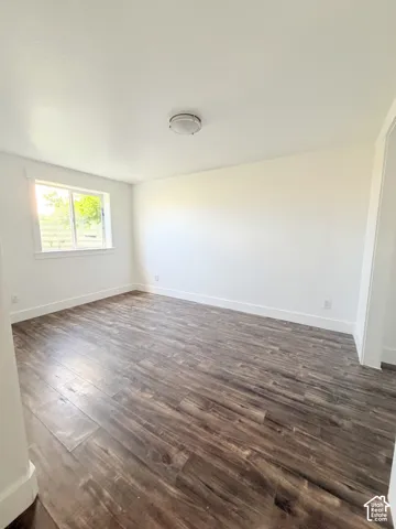 Spacious interior room featuring wood-finish flooring, white baseboards, and a neutral wall palette
