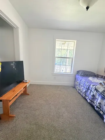 Carpeted room with white walls, baseboards, and window trim