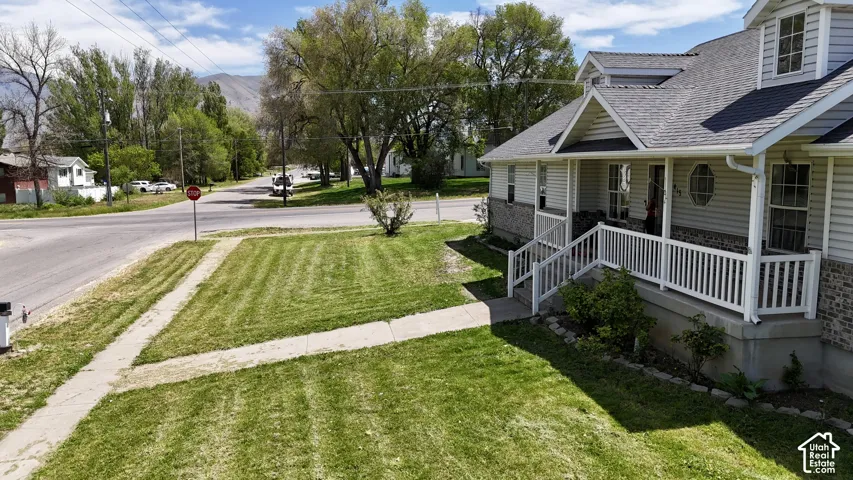 Single-family residence featuring a prominent covered porch with white railings, a light gray siding exterior, and a dark shingle roof