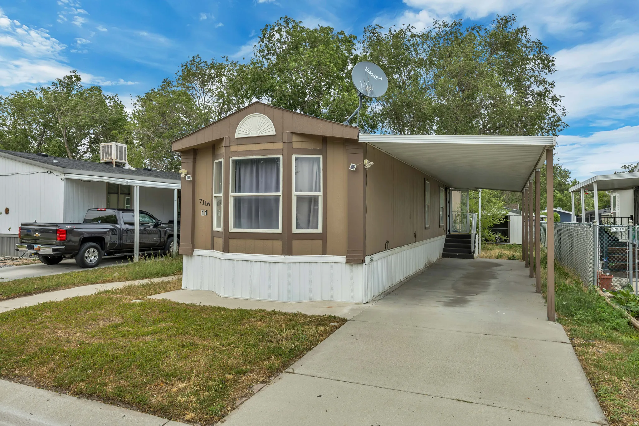 Exterior featuring a bay window, a covered carport, concrete driveway, and a white skirting foundation