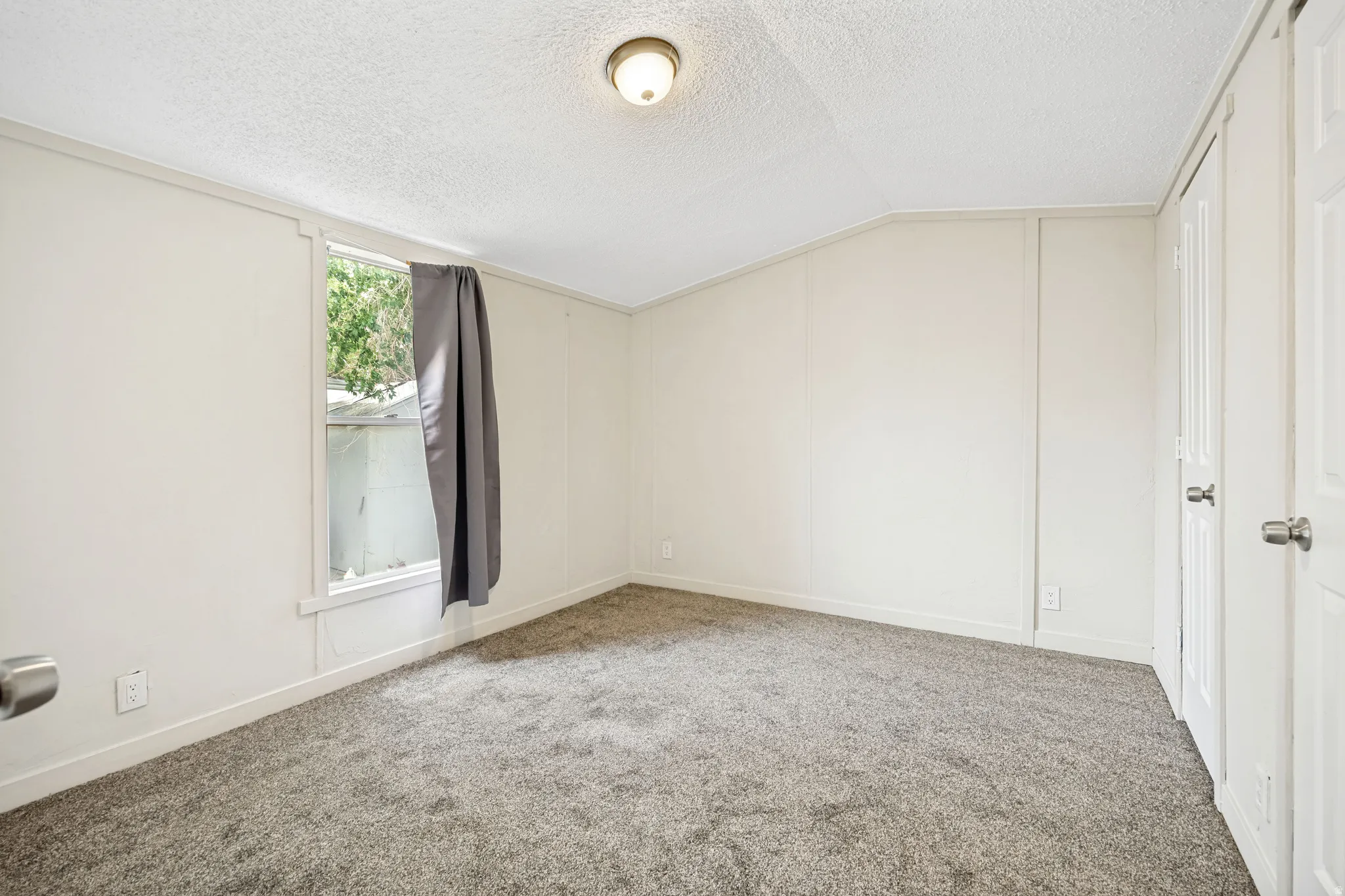 Carpeted room featuring a single window with trim, a built-in ceiling light fixture, and two panel doors