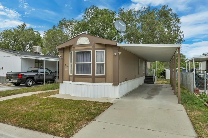 Exterior featuring a bay window, a covered carport, concrete driveway, and a white skirting foundation