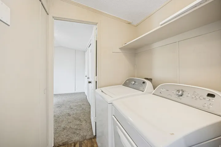 Dedicated laundry area featuring a washer and dryer, an overhead storage shelf, and wood-finish flooring