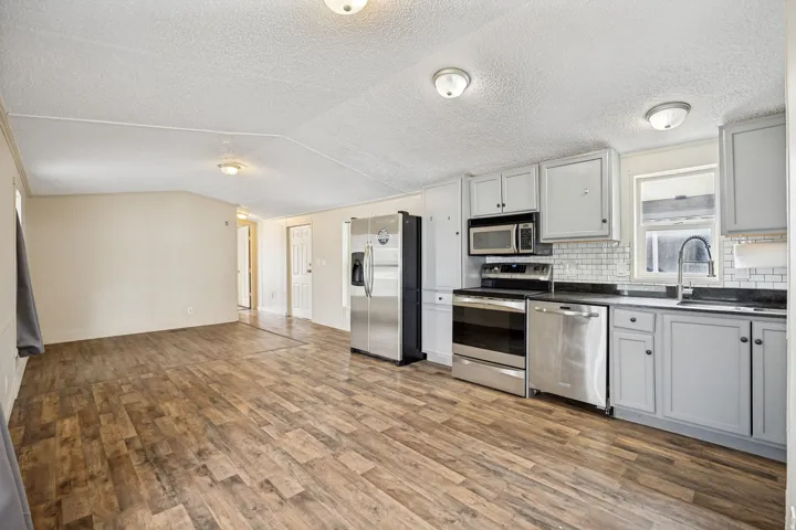 Expansive open-concept living area featuring wood-finish flooring, recessed lighting, and light-toned walls