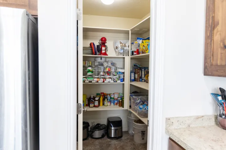 Walk-in pantry with ample shelving and a light-colored flooring