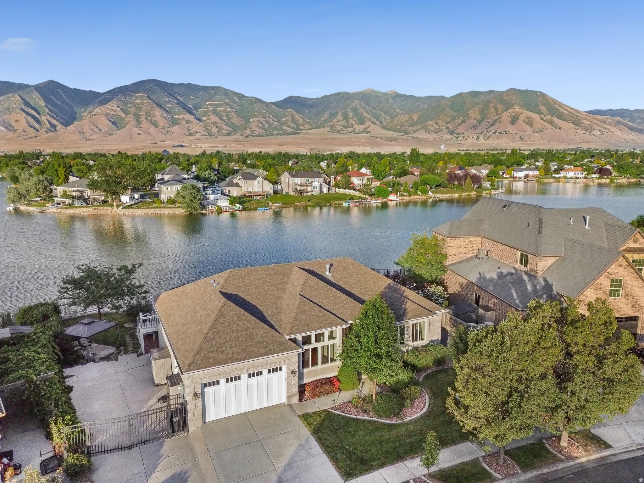 Waterfront property featuring a stone and brick facade, an attached two-car garage, and a gated driveway