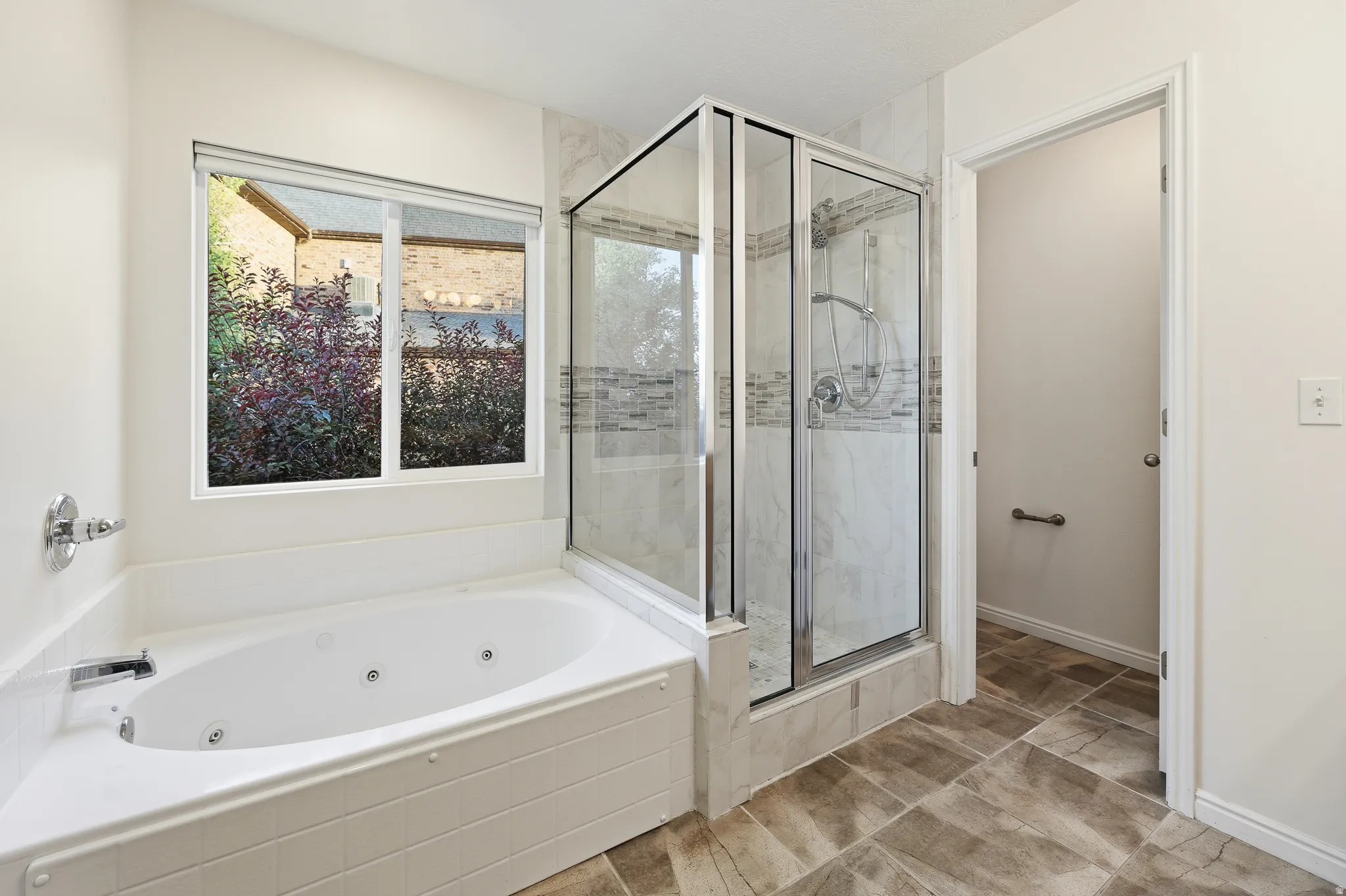 Primary Bath. Corner jetted soaking tub and glass-enclosed shower with tile surround