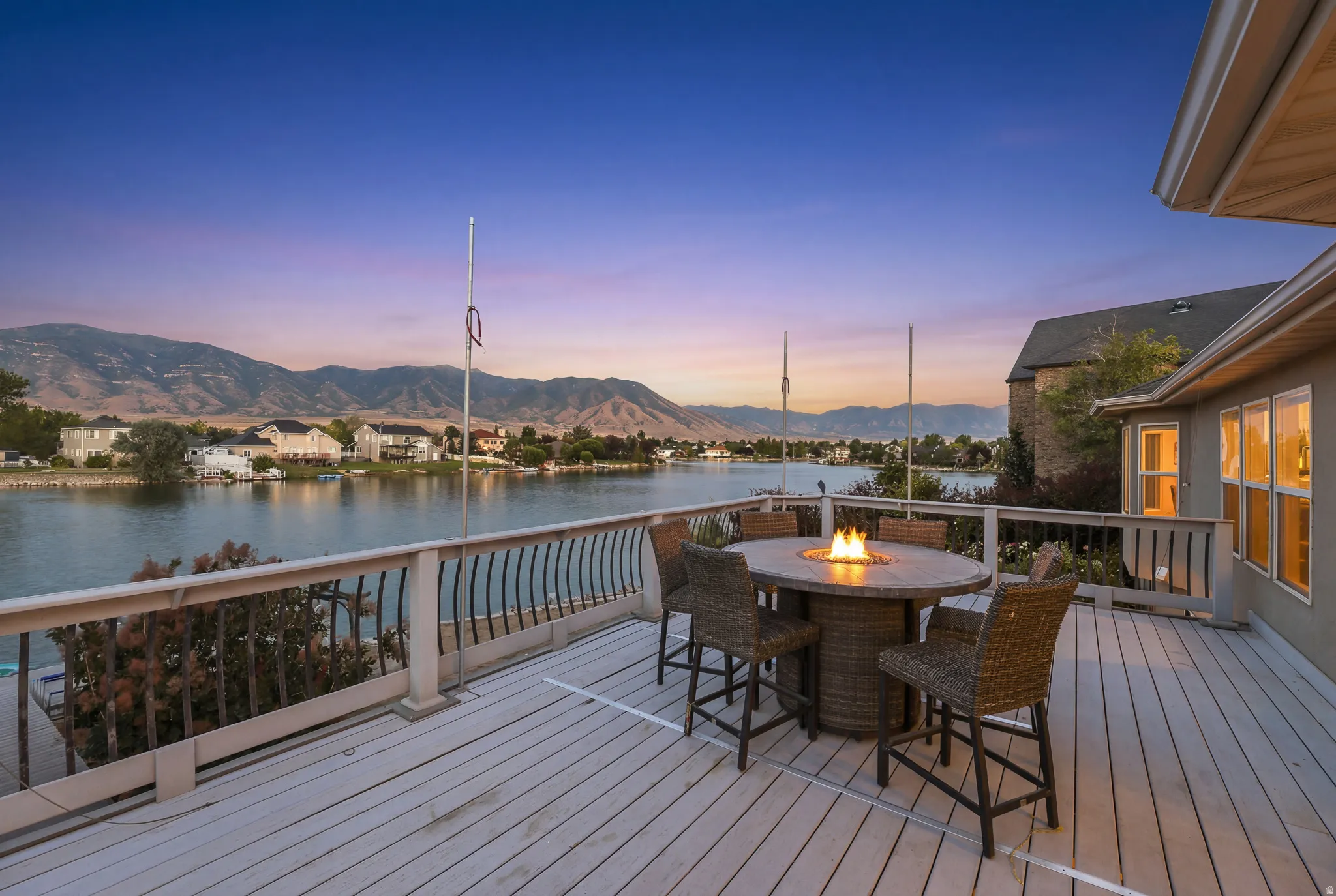 Expansive waterfront deck featuring a built-in fire pit table, composite decking, and a sturdy railing overlooking the lake