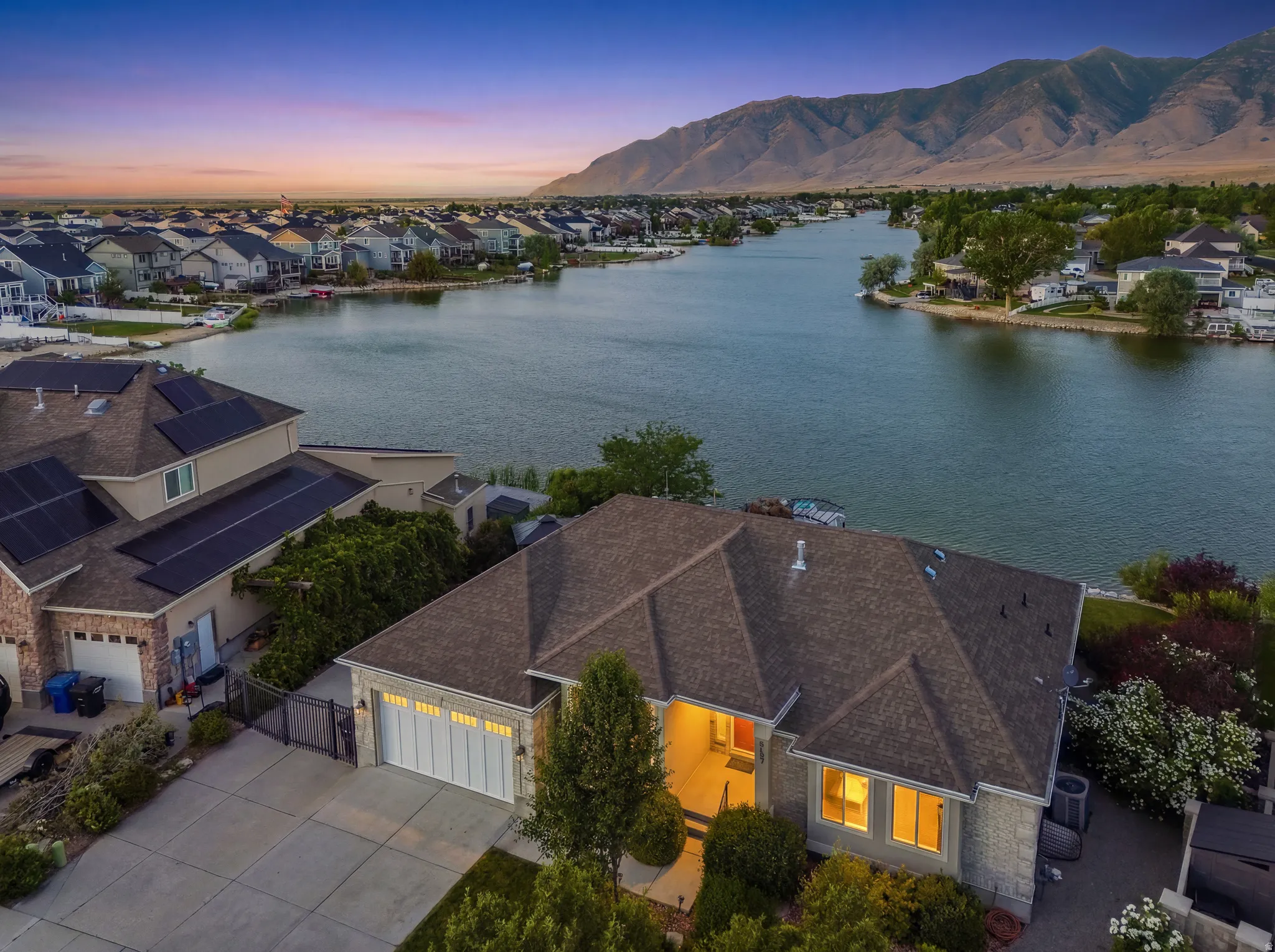 Stone and siding exterior with a multi-car driveway, attached garage, and a lush front landscape