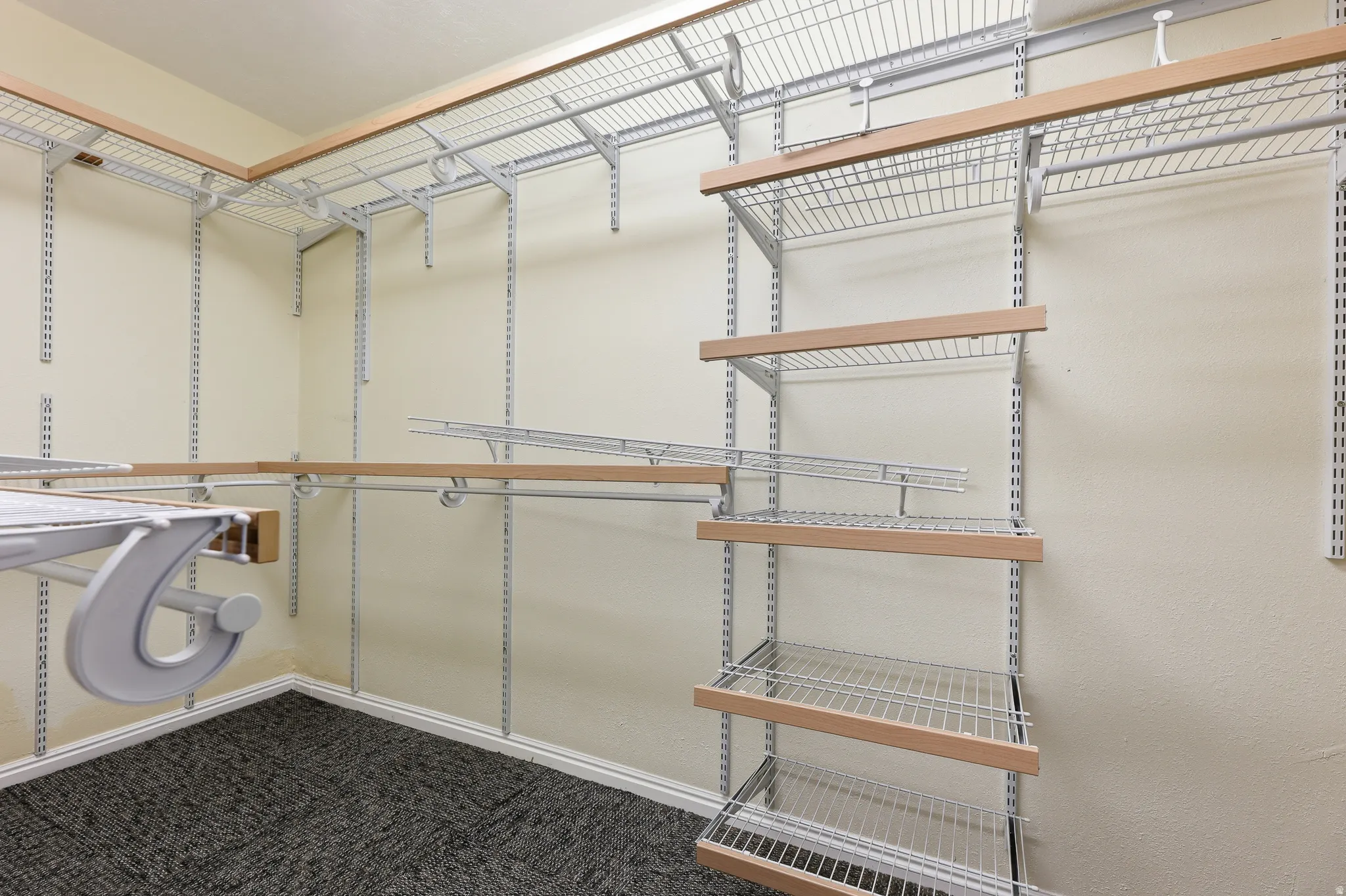 Walk-in closet featuring wire shelving, wood-finish accents, and textured carpet flooring